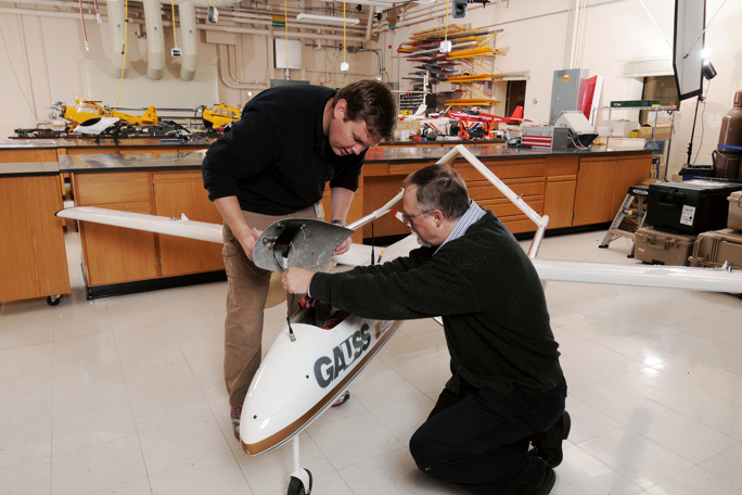 Mike Heiges, kneeling, and Warren Lee install a sensor package on GTRI’s flying UAV test bed, GAUSS.Georgia Tech Research Institute